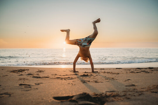 Young boy doing cartwheels at beach sunset in Spain