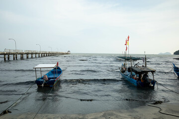 Anchored small Malaysian fisherman boats riding the waves in the afternoon