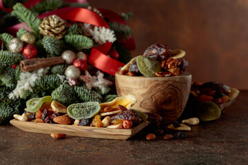 Dried fruits and nuts with Christmas wreath on a brown vintage table.