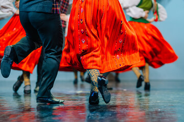  Latvian Folk dancers in vibrant green and red traditional costumes perform a lively dance on...