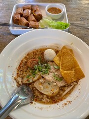 The closed up of Thai noodles with meat ball. Select and soft focus. Asian noodle soup with beef meatball with fresh vegetable on wood table. Hot and spicy noodle soup, Asian food.
