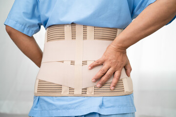 Asian lady patient wearing back pain support belt for orthopedic lumbar with walker.