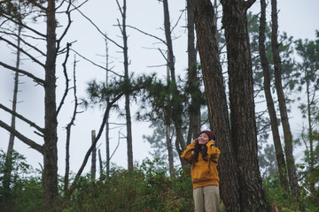 Portrait image of a woman with closed eyes holding hat in the forest