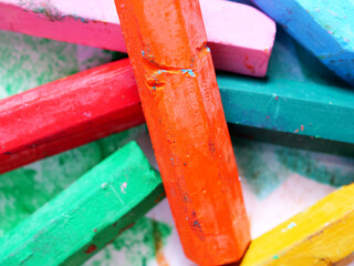 used and broken colored crayons on painted paper background
