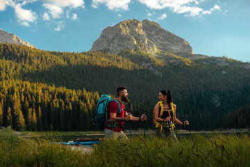 Two hikers on a mountain trail by a lake
