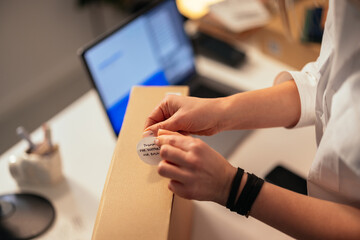 Person attaching thank you note to a parcel