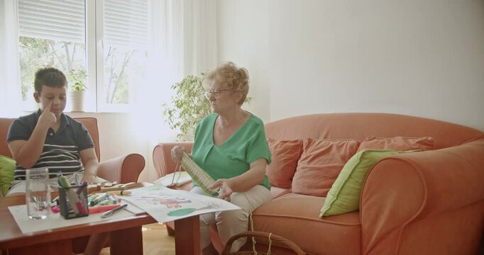 A heartwarming scene of a grandmother knitting while her grandson draws, showcasing the joys of family and inter generational connection.