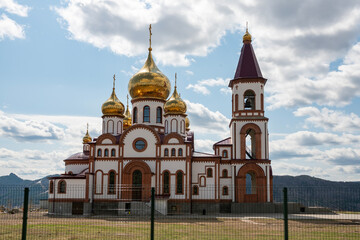 Church with golden domes against a cloudy sky.