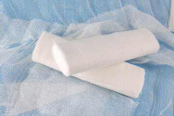 Gauze medical bandage on a blue background. Two rolls of bandage and a bandage strip.
