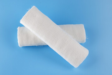 Gauze medical bandage on a blue background. Cross made from rolls of bandage on a blue background.