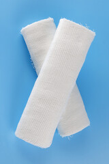 Gauze medical bandage on a blue background. Cross made from rolls of bandage on a blue background.
