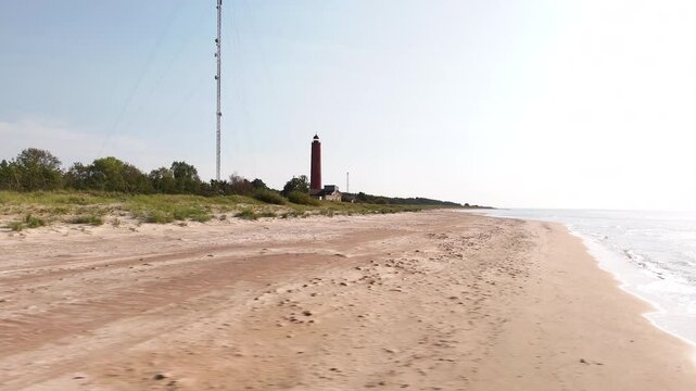 Drone travel at isolated lighthouse on the beach, revealing sea waves, landscape