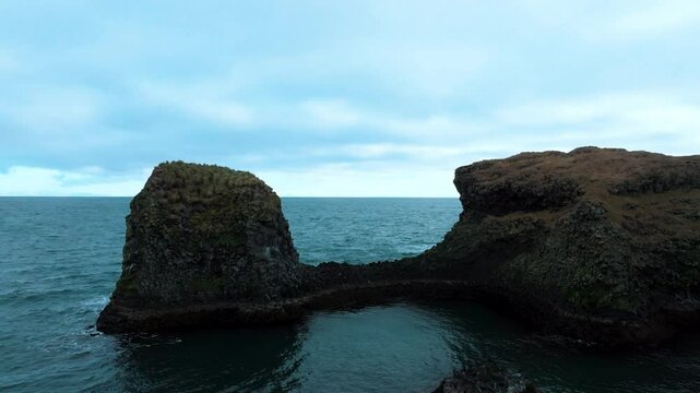 Flying along Iceland's black sea cliffs and between basalt lava formations towards the ocean horizon