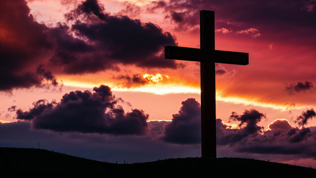 Large christian cross standing on hill at sunset with dramatic clouds