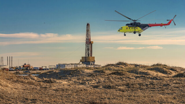 Oil and gas field in the Arctic. Summer. Sandy landscape with small lakes. Drilling rig. Flying helicopter.