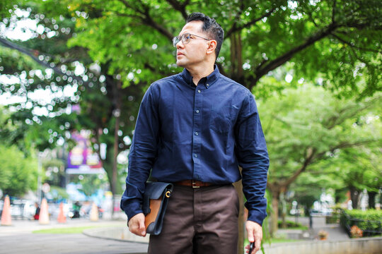 Portrait Of Businessman Walking on Park While Holding Briefcase - Powered by Adobe