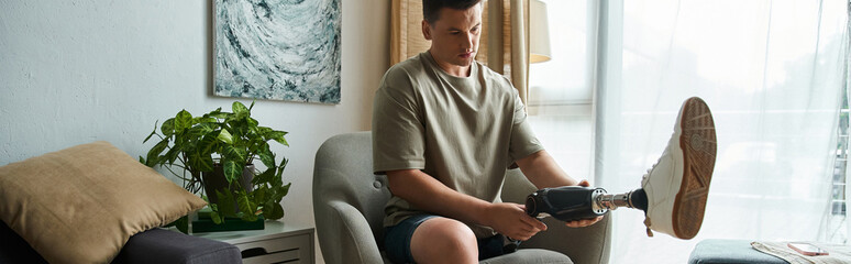 Fototapeta premium Handsome young man makes adjustments to his prosthetic leg in a modern living space.