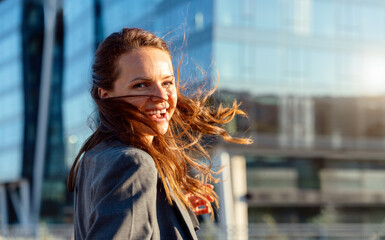 Joyful urban woman with hair flowing in motion walking outdoors on a city street.