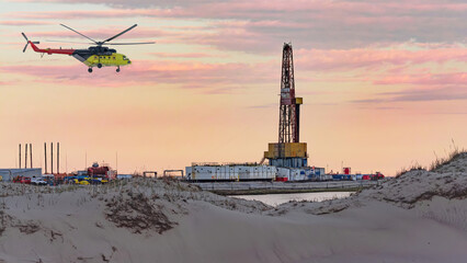 Oil and gas field in the Arctic. Summer. Sandy landscape with small lakes. Drilling rig. Flying helicopter. © vladend