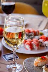 Glass of White Wine Against a Set Table with Sushi
