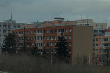 Obraz premium In the image, there is a row of buildings situated prominently, with lush green trees in the foreground, and a cloudy sky gracefully filling the background