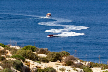 sport boasts driving fast with big waves behind them at the coast of Comino, Malta 