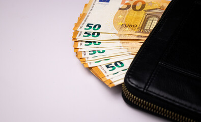 Black leather wallet with fifty euro bills banknotes on white background 
