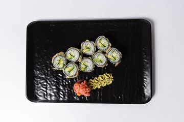 Salmon skin sushi roll served on a black stone, top view