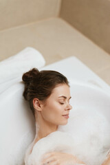 Naklejka premium Relaxed European woman enjoying a bubble bath in a serene bathroom setting, feeling peaceful and rejuvenated. Self-care and wellness concept.