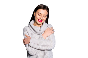 Portrait of positive woman cuddling herself with eyes closed wearing grey woolen pullover isolated over blue background