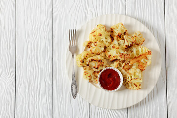 fried cauliflower florets on white plate, top view