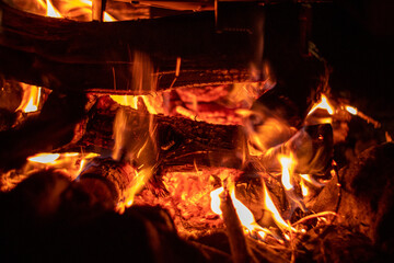A mesmerizing view showcases glowing embers and flickering flames in a warm and cozy campfire setting, close-up background
