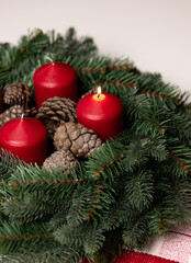 Close up of an advent wreath with one red burning candle on white table 