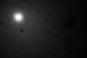 Full moon astral sky with milky clouds. Dramatic clouds in mystic moonlight. Moon illuminating a dark, cloudy night sky