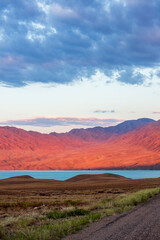 Breathtaking scenic morning view of the red Tien-Shan mountains and Bartogay Lake, showcasing the stunning natural beauty of Kazakhstan near Almaty. Copy space, vertical.