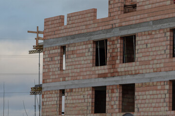 A sturdy brick building is currently under construction on a rather cloudy day, adding to the atmosphere of the ongoing project