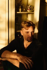 Close-up portrait of handsome young Caucasian man emotionless expression serious face against apartment background