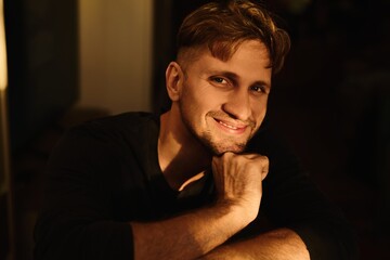 Close-up portrait of handsome young Caucasian man smiling against apartment background