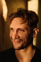 Close-up portrait of handsome young Caucasian man smiling against apartment background