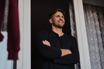 Close-up portrait of handsome young Caucasian man smiling against apartment background