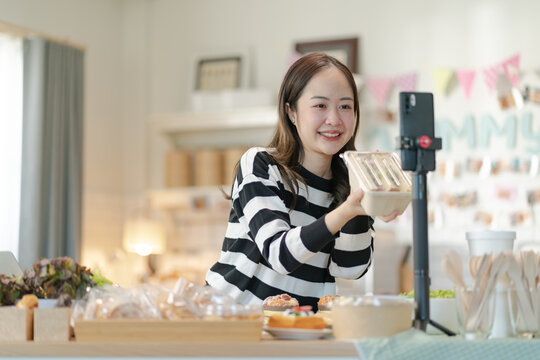 Beautiful asian girl sell online bakery shop at home,family business,online influencer,start-up business.happyness Beautiful woman to take orders from customers,live-stream their sandwiches online