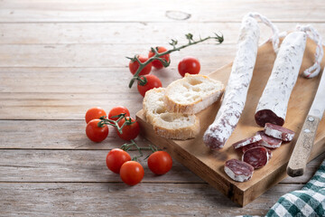 Fuet.Dry cured fuet sausage on wooden table. Copy space