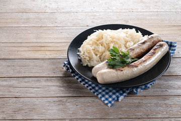 Bratwurst sausage and sauerkraut on wooden table. Copy space