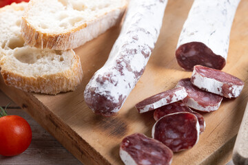 Fuet.Dry cured fuet sausage on wooden table. Close up