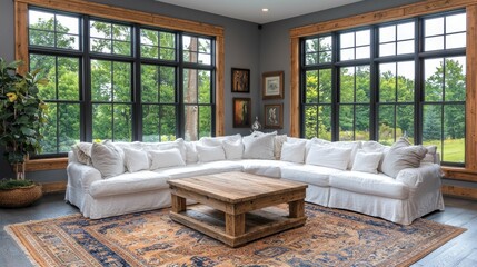 A beautifully designed living room featuring a large, white fabric sectional sofa, wooden coffee table, and expansive windows overlooking nature.