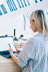 Millennial woman using modern cellphone and laptop devices for sharing files via bluetooth...