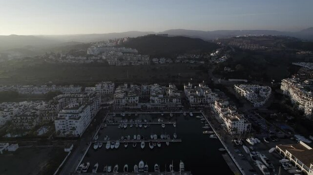 "Drone footage at sunset over La Duquesa Port in Sabinillas, M&aacute;laga. A bird's-eye retreating shot reveals docked boats, the marina, and the serene coastal beauty of this Andalusian harbor."