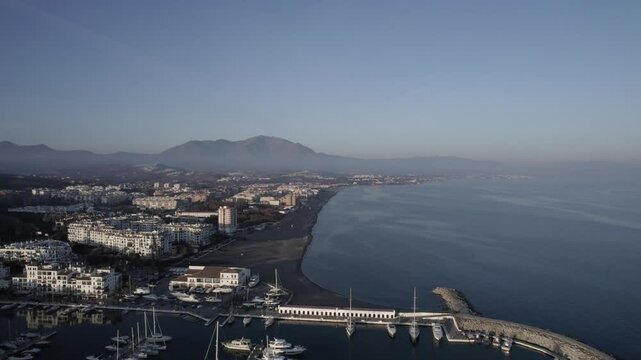 "Drone footage at sunset over La Duquesa Port in Sabinillas, M&aacute;laga. A retreating shot showcases docked boats, the marina, and the tranquil charm of this Andalusian coastal harbor."