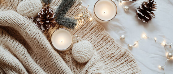 Cozy layout of knitted sweater, yarn, cones, candle, fir, decoration. Winter template for holidays. Flat lay. Hygge minimal themes. Mockup for seasonal and lifestyle content. Generative ai