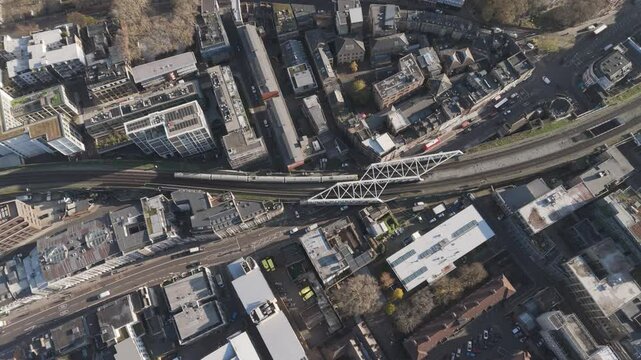 Top-down aerial view of an overground train making its way through London&rsquo;s bustling streets, capturing urban movement
